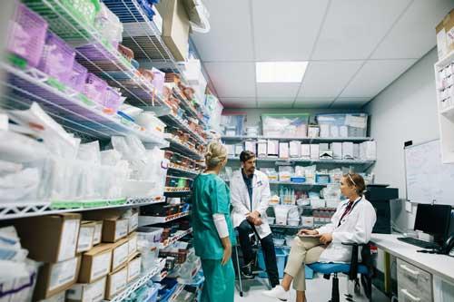 Three providers talk in hospital pharmacy